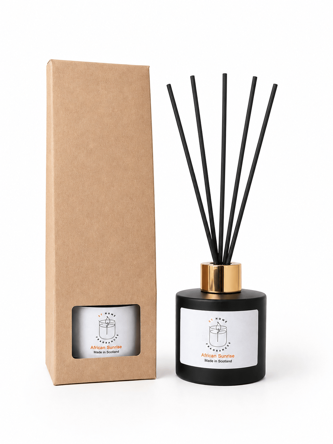 A reed diffuser bottle with black reeds and a gold collar stands next to its tall brown kraft paper box on a white background.