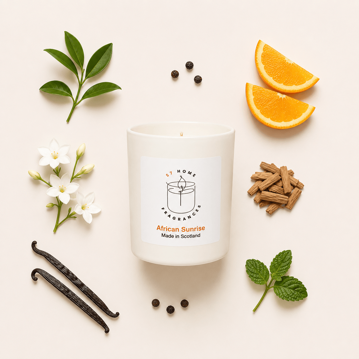 A white scented candle labeled 'S7 Home Fragrance African Sunrise Made in Scotland' arranged in a flat lay with orange slices, vanilla beans, white flowers, cinnamon sticks, and mint leaves on a light beige background.