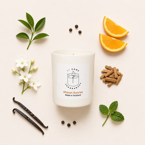 A white scented candle labeled 'S7 Home Fragrance African Sunrise Made in Scotland' arranged in a flat lay with orange slices, vanilla beans, white flowers, cinnamon sticks, and mint leaves on a light beige background.