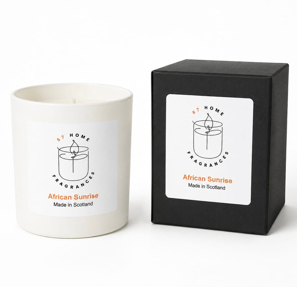 A white wax candle jar next to its black square packaging box, both featuring a white label with the brand name 'S7 Home Fragrances' and the scent 'African Sunrise'.