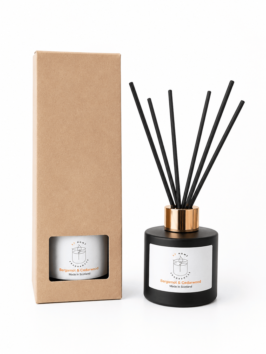 A reed diffuser bottle with black reeds, a black glass body, and a gold collar stands next to its plain brown cardboard box on a white background.