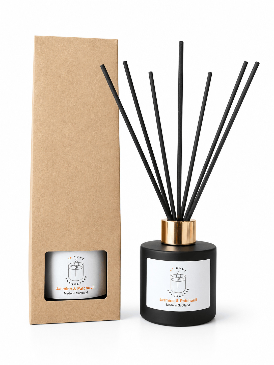 A reed diffuser bottle with black reeds and a gold collar stands next to its tall brown kraft paper box on a white background. The bottle has a white label with a simple line drawing and the text 'Jasmine & Patchouli' and 'Made in Scotland'.
