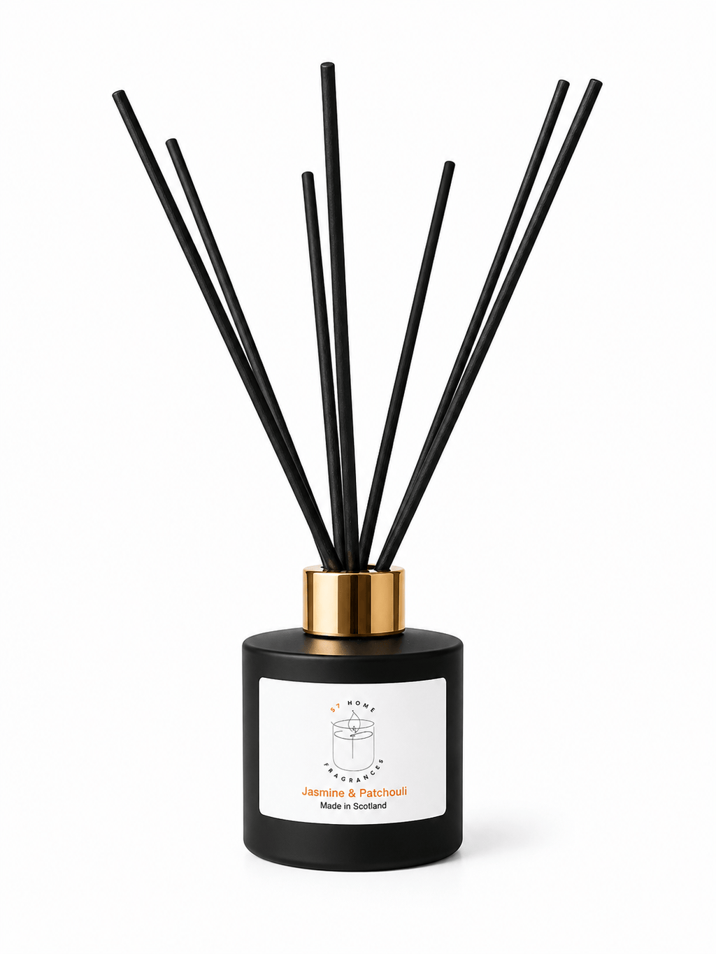 A reed diffuser bottle with a matte black cylindrical base, a metallic gold collar, and multiple black reed sticks, shown on a clean white background. The front label reads 'Jasmine & Patchouli' with a small orange accent, made in Scotland by S7 Home Fragrances