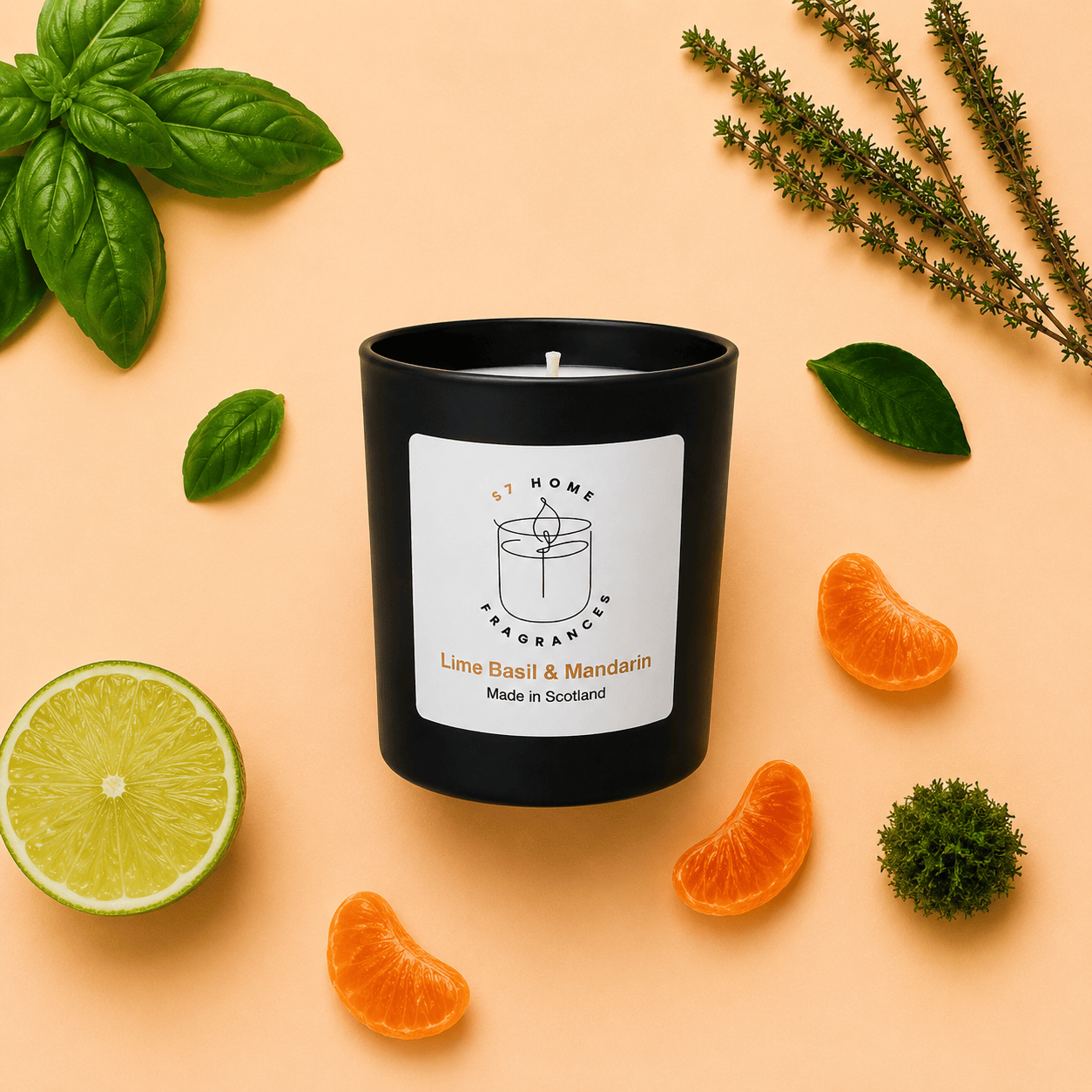 A black scented candle jar with a white label reading 'S7 Home Fragrances' and 'Lime Basil & Mandarin' sits on a peach background, surrounded by fresh lime, orange slices, basil leaves, and green sprigs.