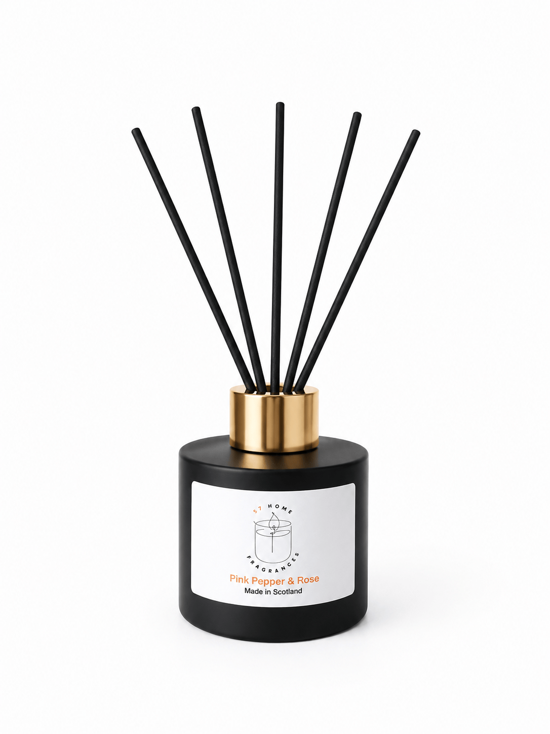 A reed diffuser bottle with a matte black cylindrical base, a metallic gold collar, and six black reeds extending upward. A white label on the front reads 'S7 Home Fragrance' and 'Pink Pepper & Rose'.