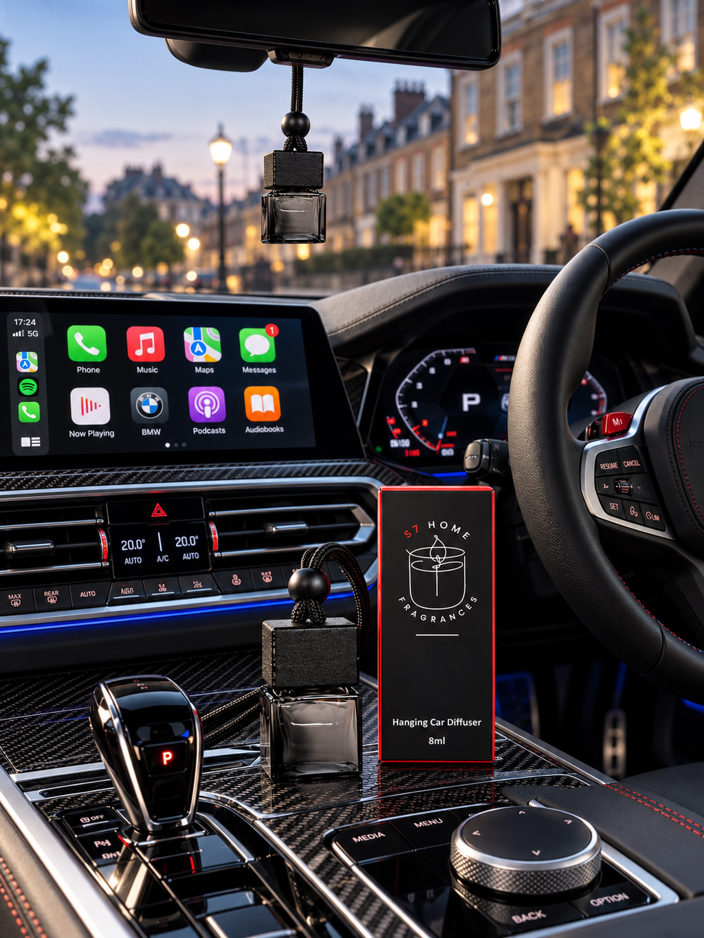 A car interior with a small hanging car diffuser bottle. A red box labeled 'S7 Home Fragrances' stands on the central console.