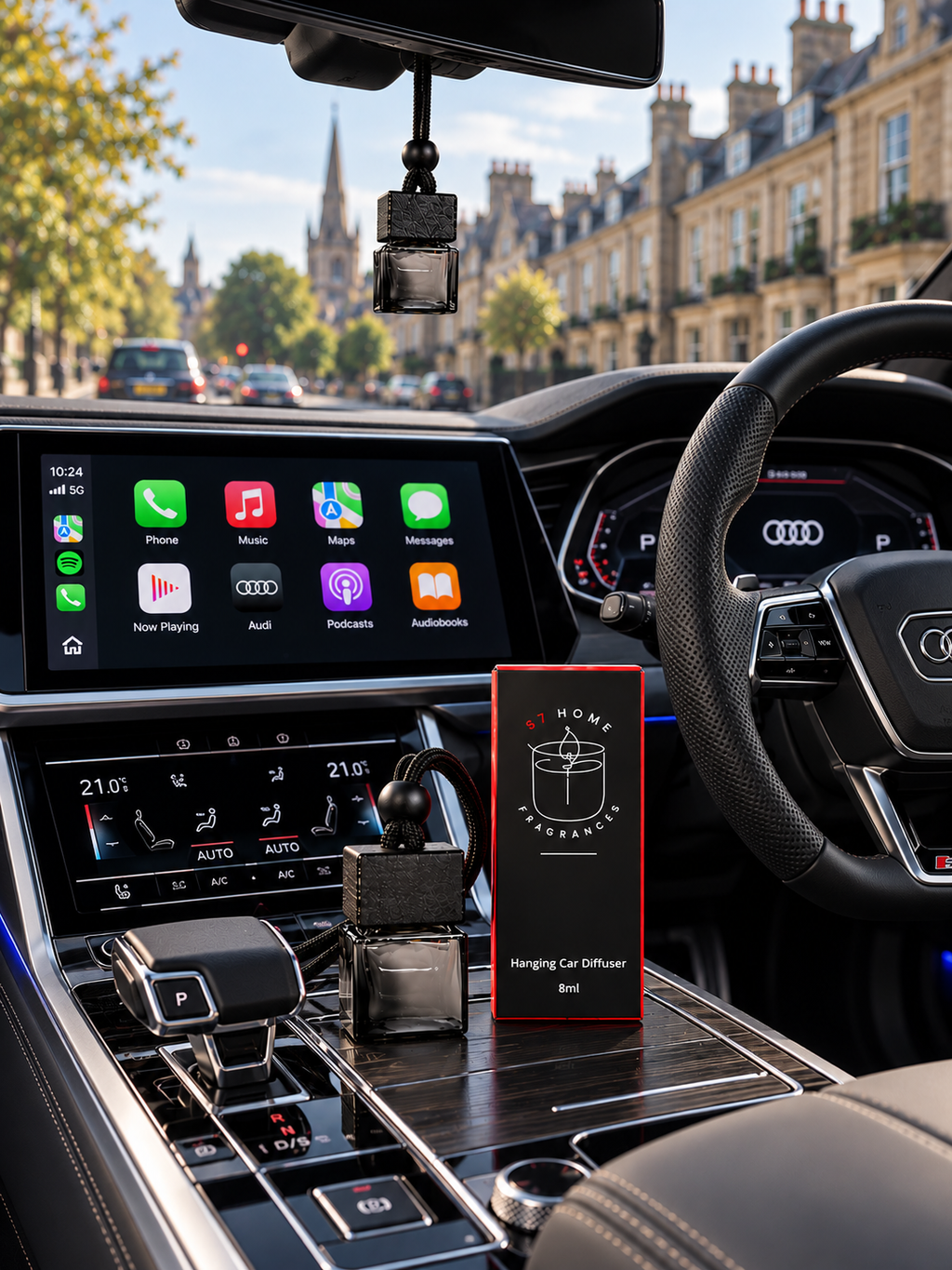 A car interior with a small hanging car diffuser bottle. A red box labeled 'S7 Home Fragrances' stands on the central console.