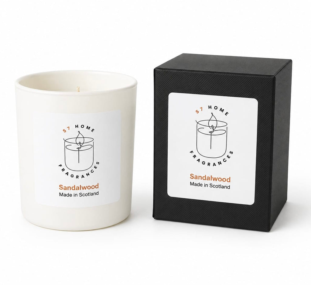 A white wax candle in a white glass vessel next to its black textured packaging box, both featuring a white label with the brand 'S7 Home Fragrances' and scent name 'Sandalwood'.