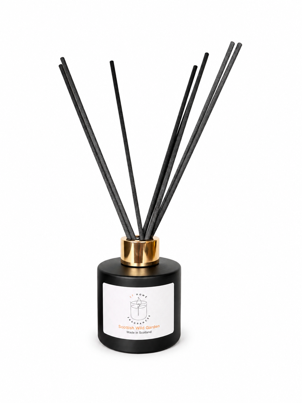 A reed diffuser bottle with a matte black cylindrical base, a white front label, and multiple black reed sticks extending upward through a gold collar, shown on a plain white background.