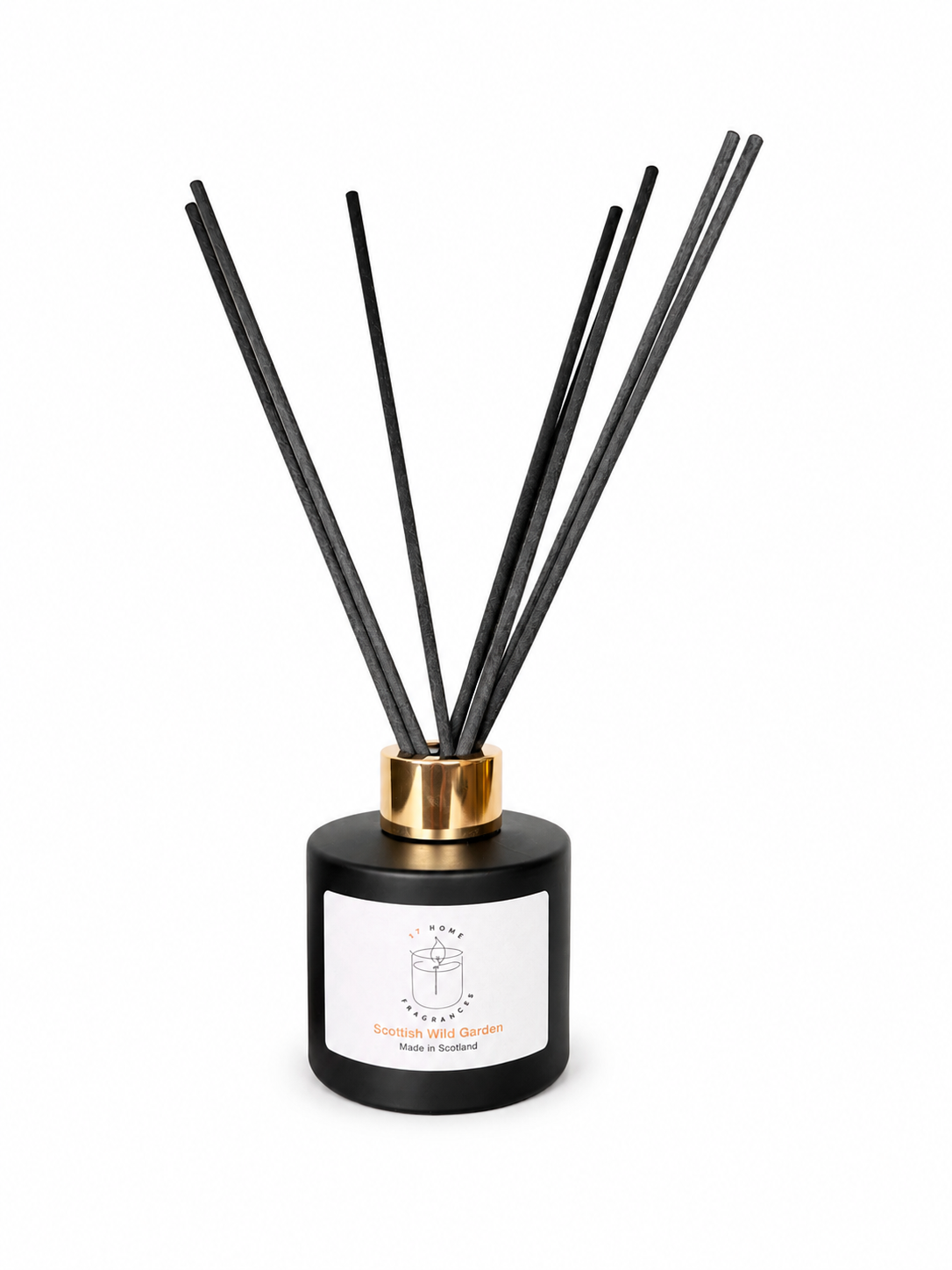 A reed diffuser bottle with a matte black cylindrical base, a white front label, and multiple black reed sticks extending upward through a gold collar, shown on a plain white background.